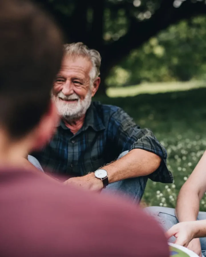 man sitting on grass talking to people
